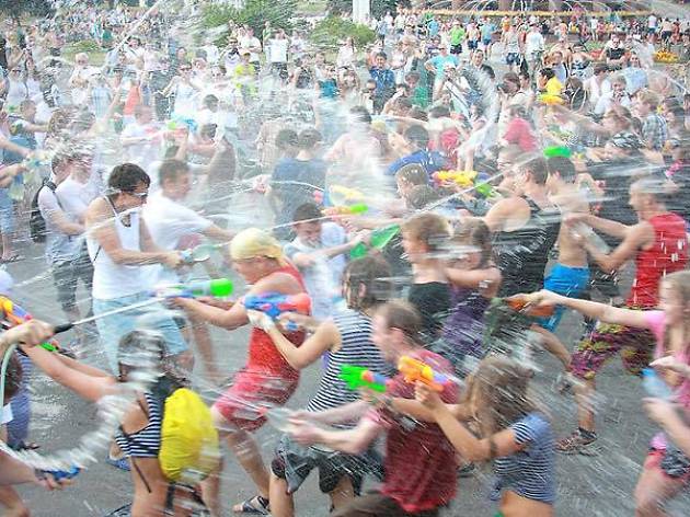 A group of people playing with water guns on a street.