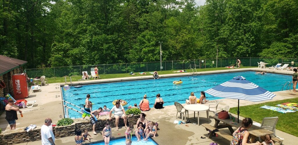A group of people at a swimming pool in a wooded area.