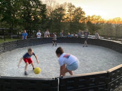 A group of kids playing soccer in a circular pit.